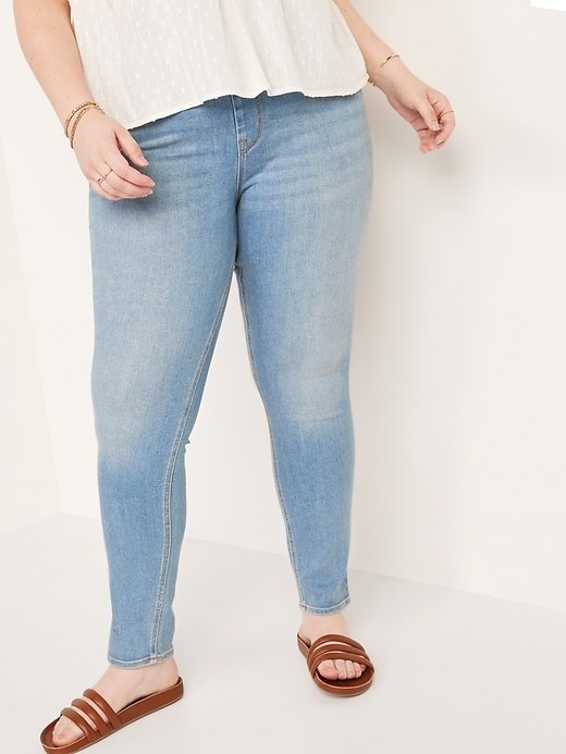 Model wearing light jeans with brown flip flops