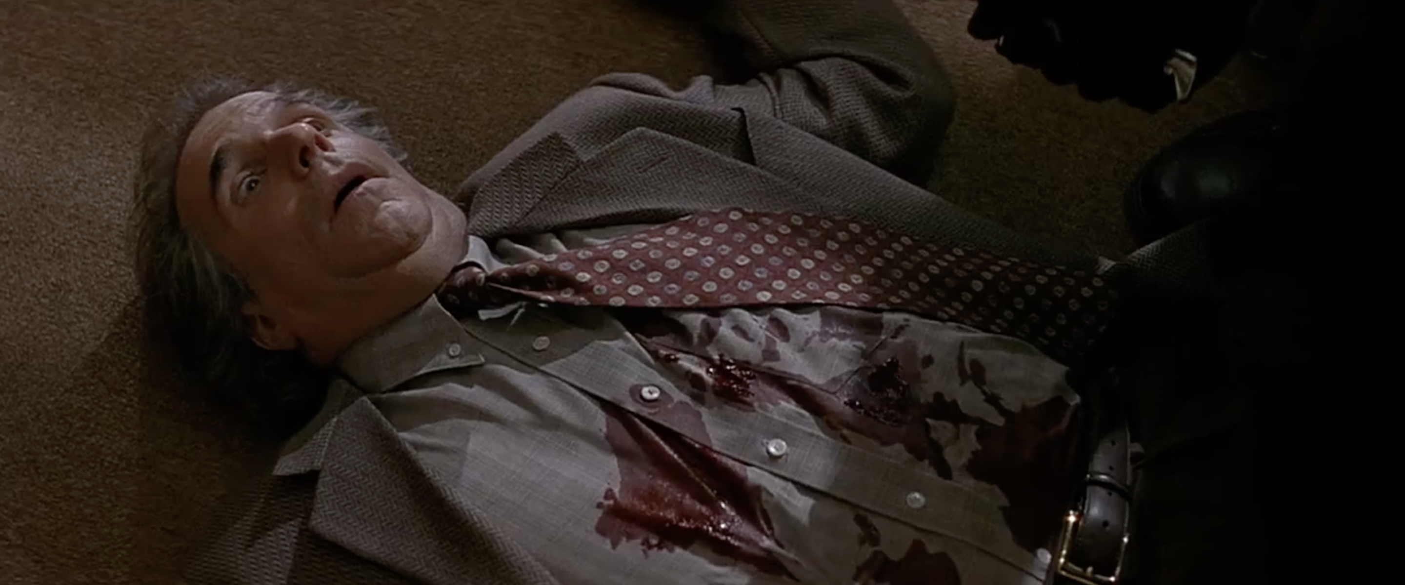 Winkler lying on the ground with a bloody shirt and eyes open