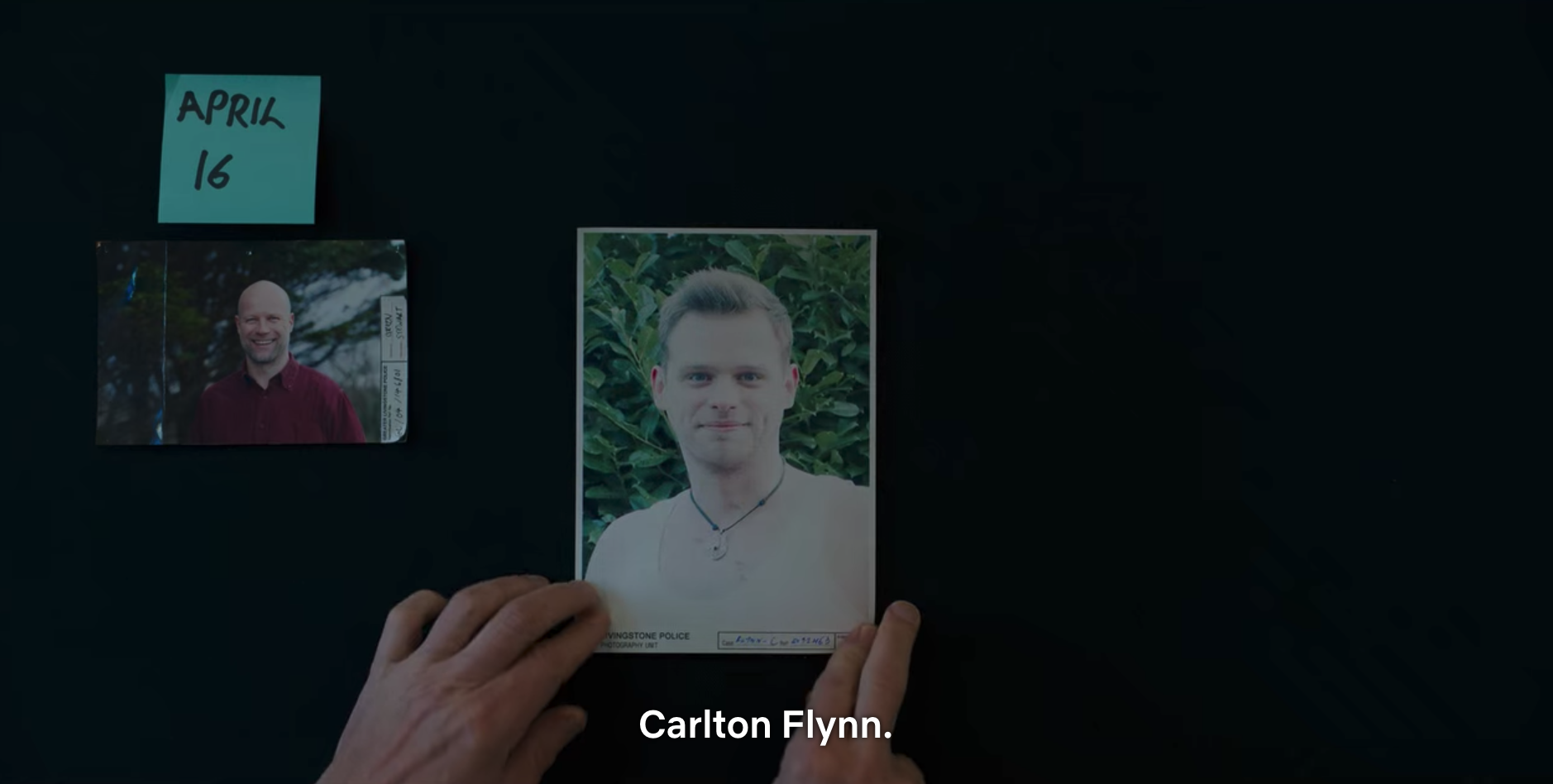Someone looking at a picture of a man with the caption Carlton Flynn next to a photograph of another man with a sticky note that says April 16 above it