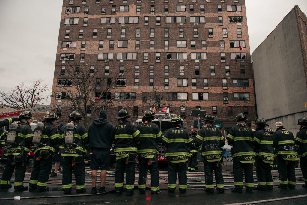 A line of firefighters standing outside the building that burned