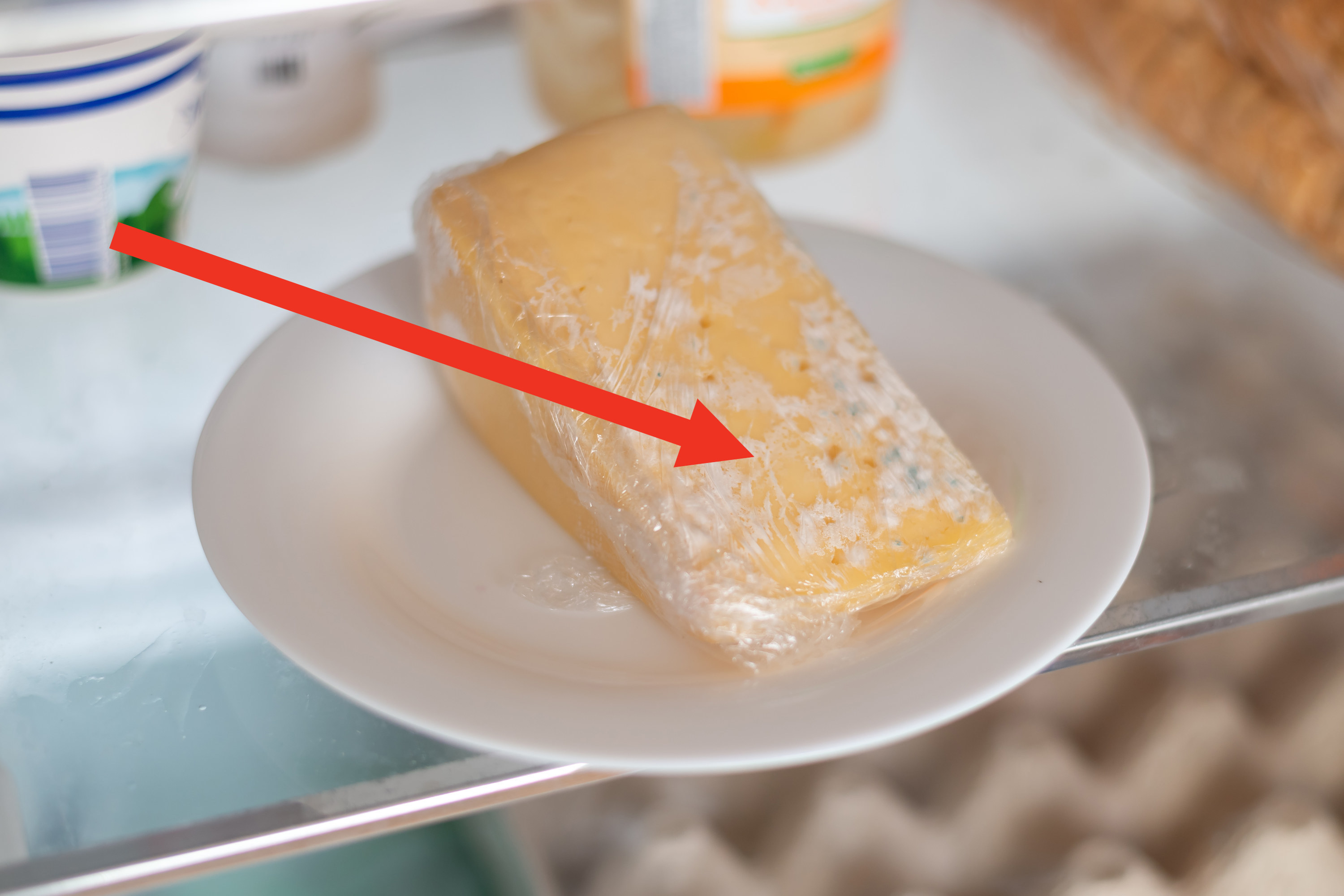 Red arrow pointing to bits of mold on a wedge of hard cheese