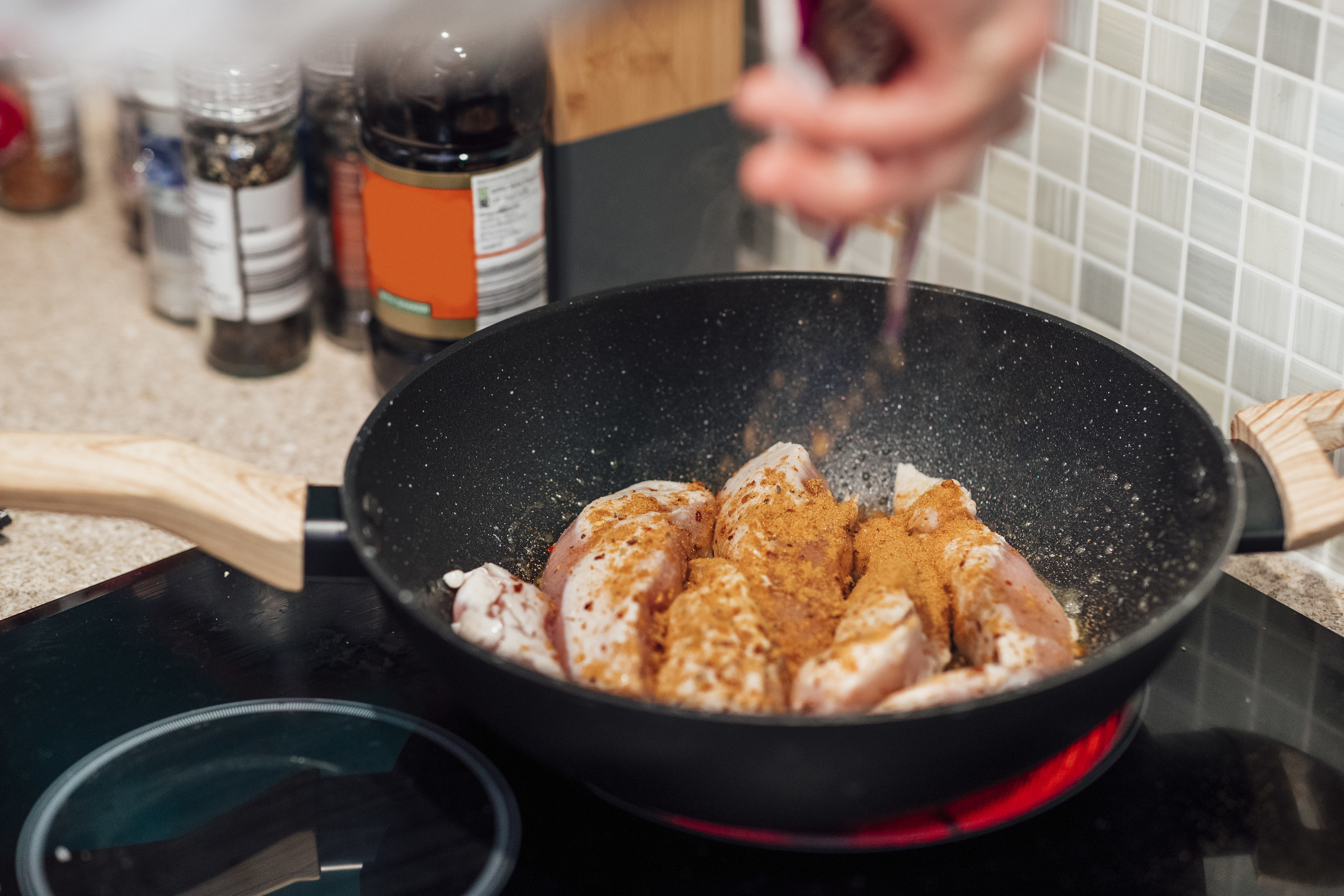 Spices on chicken in a large wok