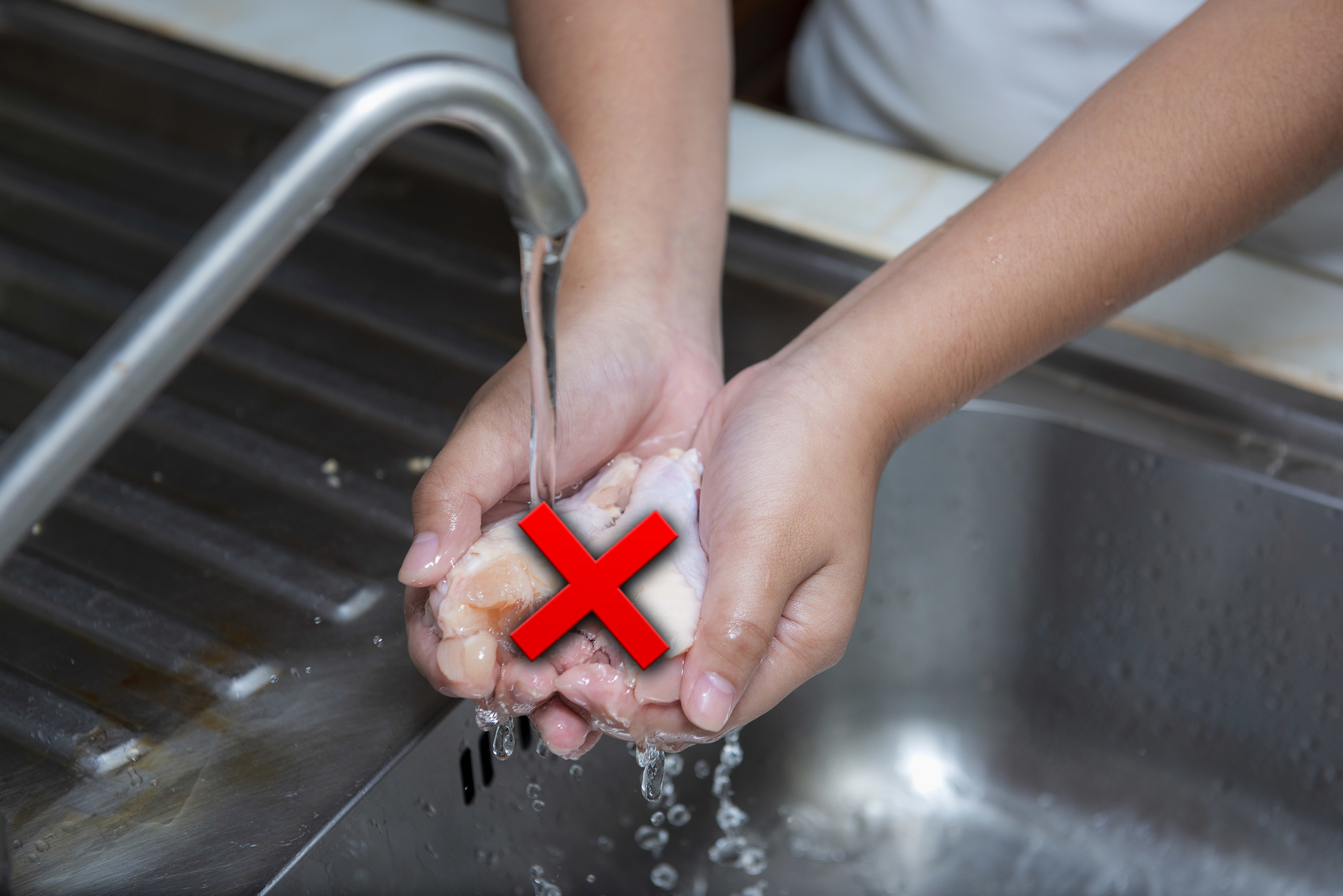 Rinsing chicken under a kitchen faucet with an X over it
