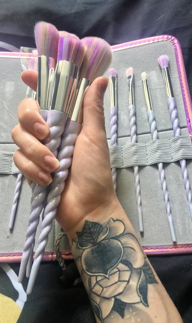 reviewer holding several unicorn makeup brushes