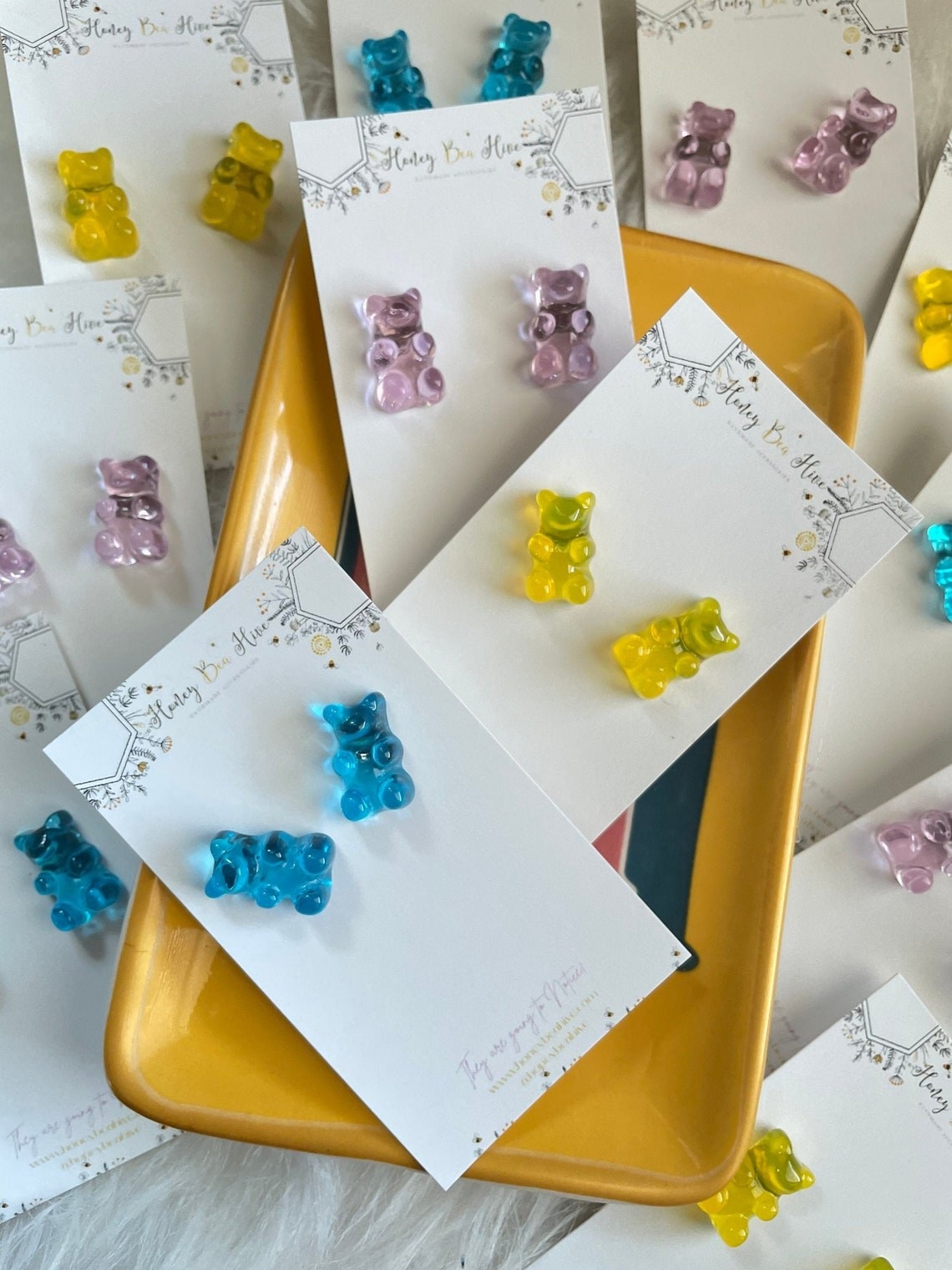 three sets of gummy bear earrings in blue, yellow, and purple