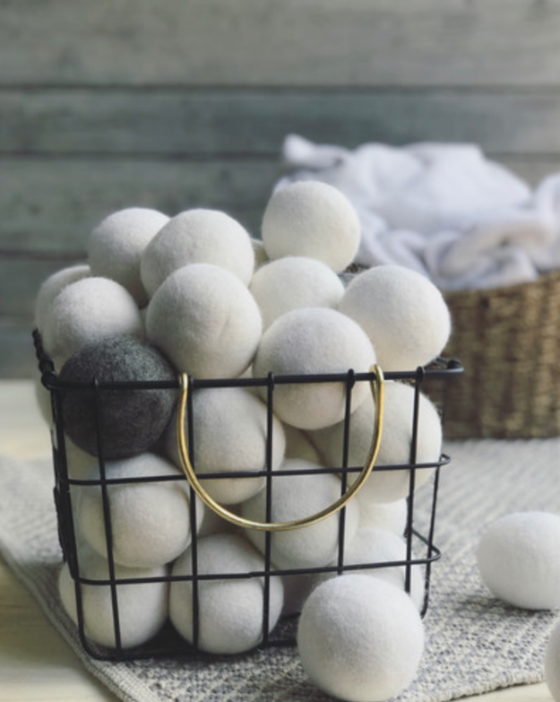 A metal basket with lots of white wool dryer balls in it
