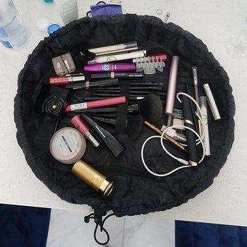 a reviewer photo of the makeup organizer spread out with various makeup products inside