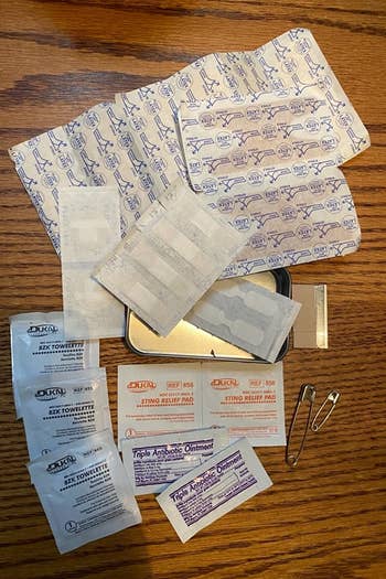 a reviewer photo of the contents of the kit: bandaids, towelettes, safety pins, and antibiotic ointment