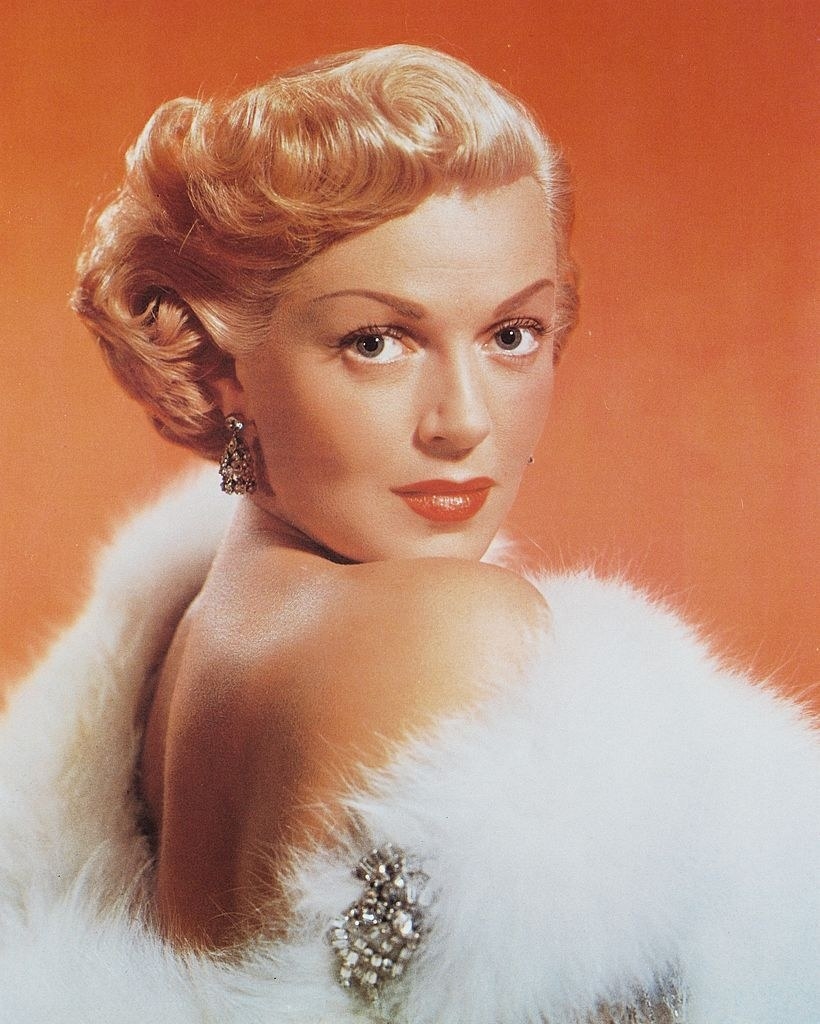 Lana Turner posing for a photo against an orange background