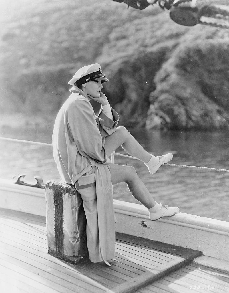 Greta Garbo sitting on a boat looking out into the ocean or lake