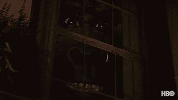 A dark face with wide eyes and smiling teeth stares through a window