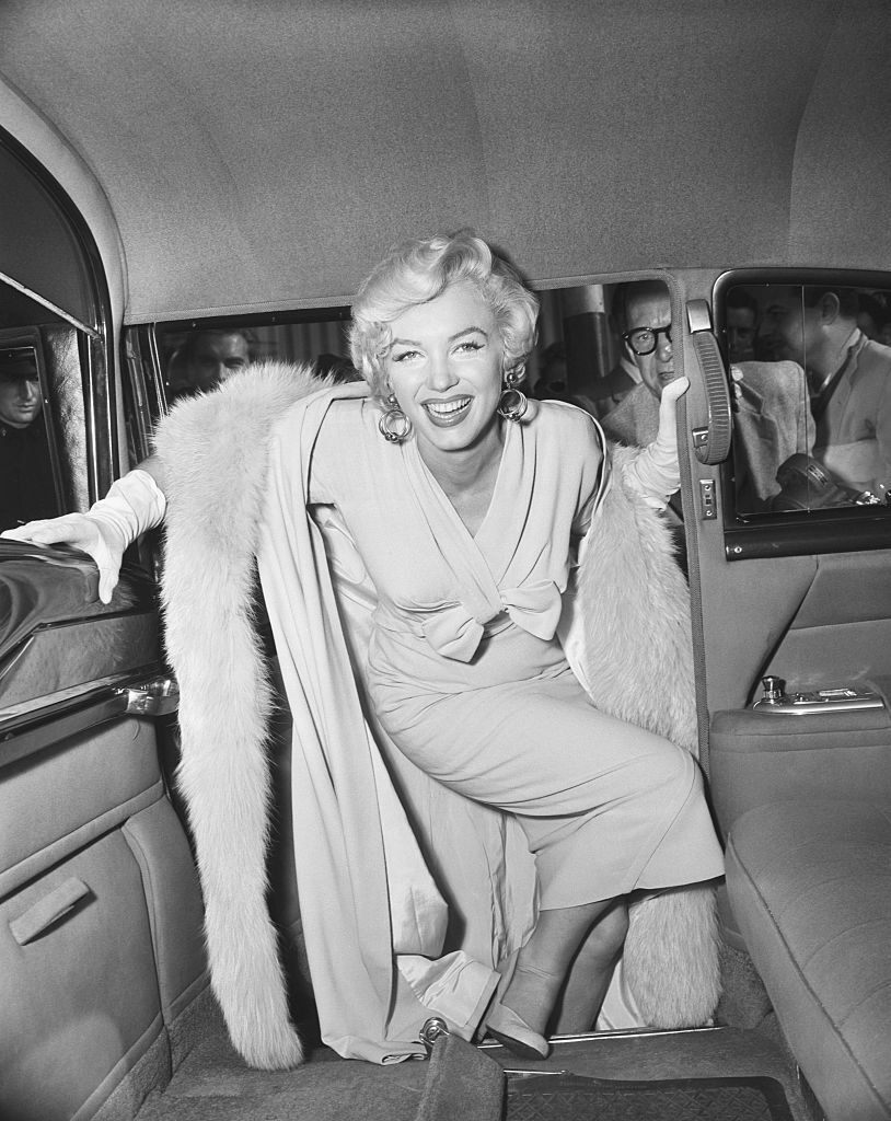 Marilyn Monroe smiling while stepping into a car