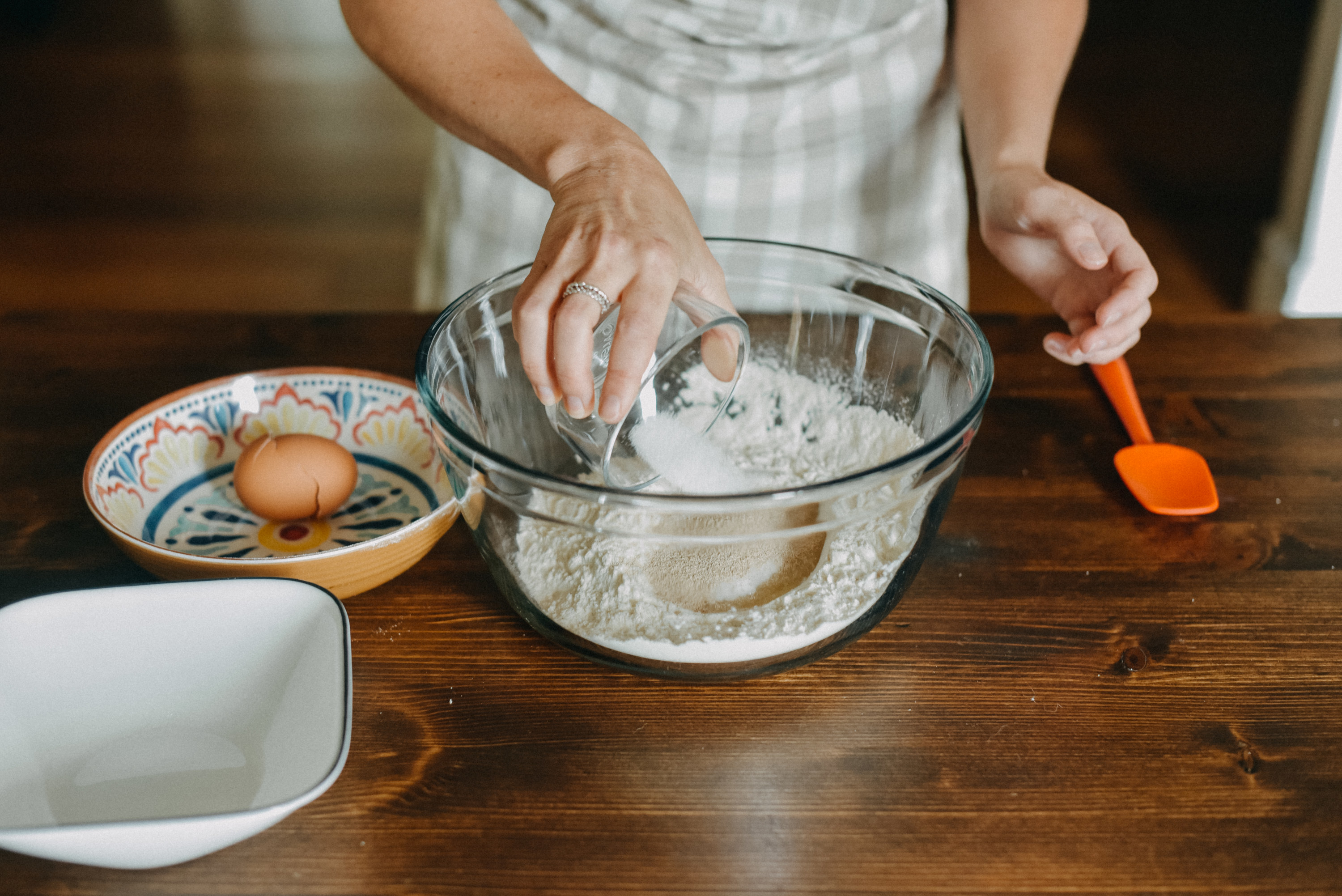 Someone pouring sugar into cake batter