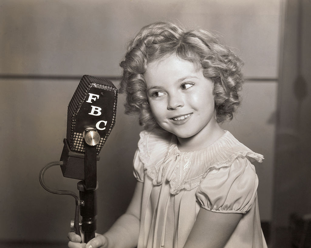 Shirley Temple holding a fbc mic smiling