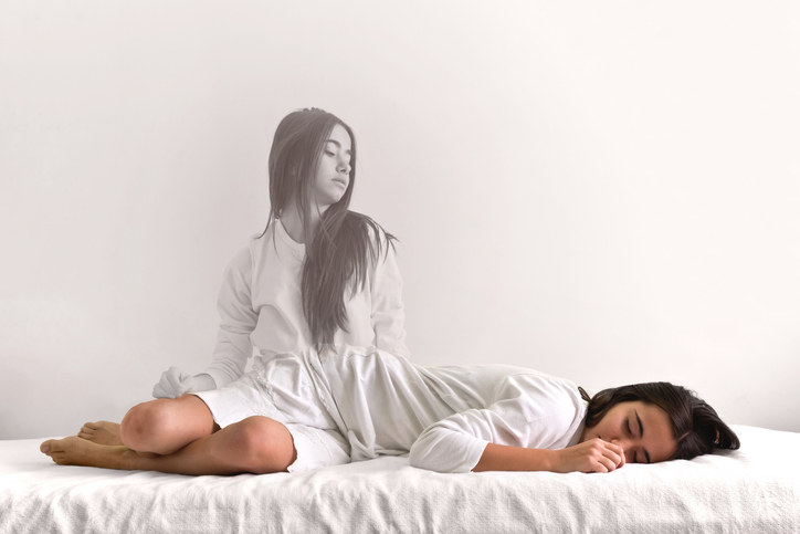 A woman&#x27;s spirit appears removed from her body, as she watches herself sleep