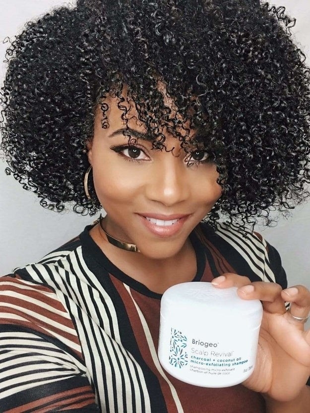 Model with beautiful natural hair holding a tub of the shampoo
