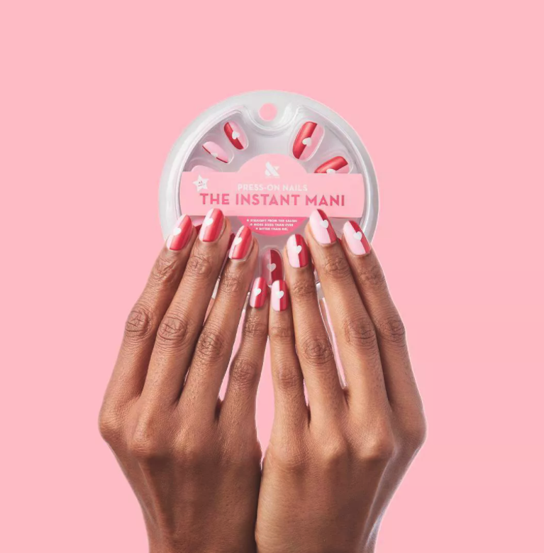 a model with press on nails that are half pink half red with a white heart in the middle