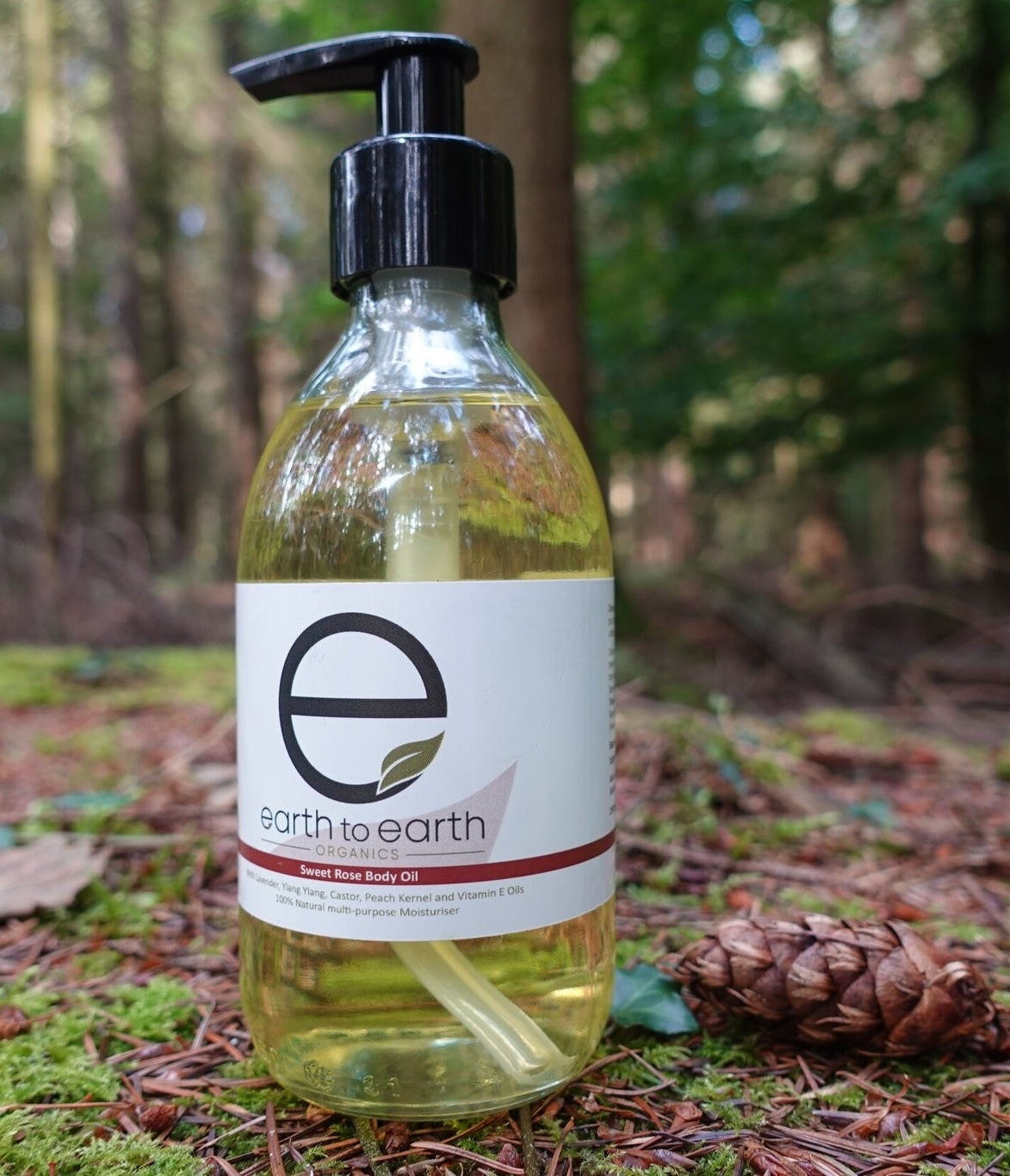Bottle of body oil with hand pump on a forest ground