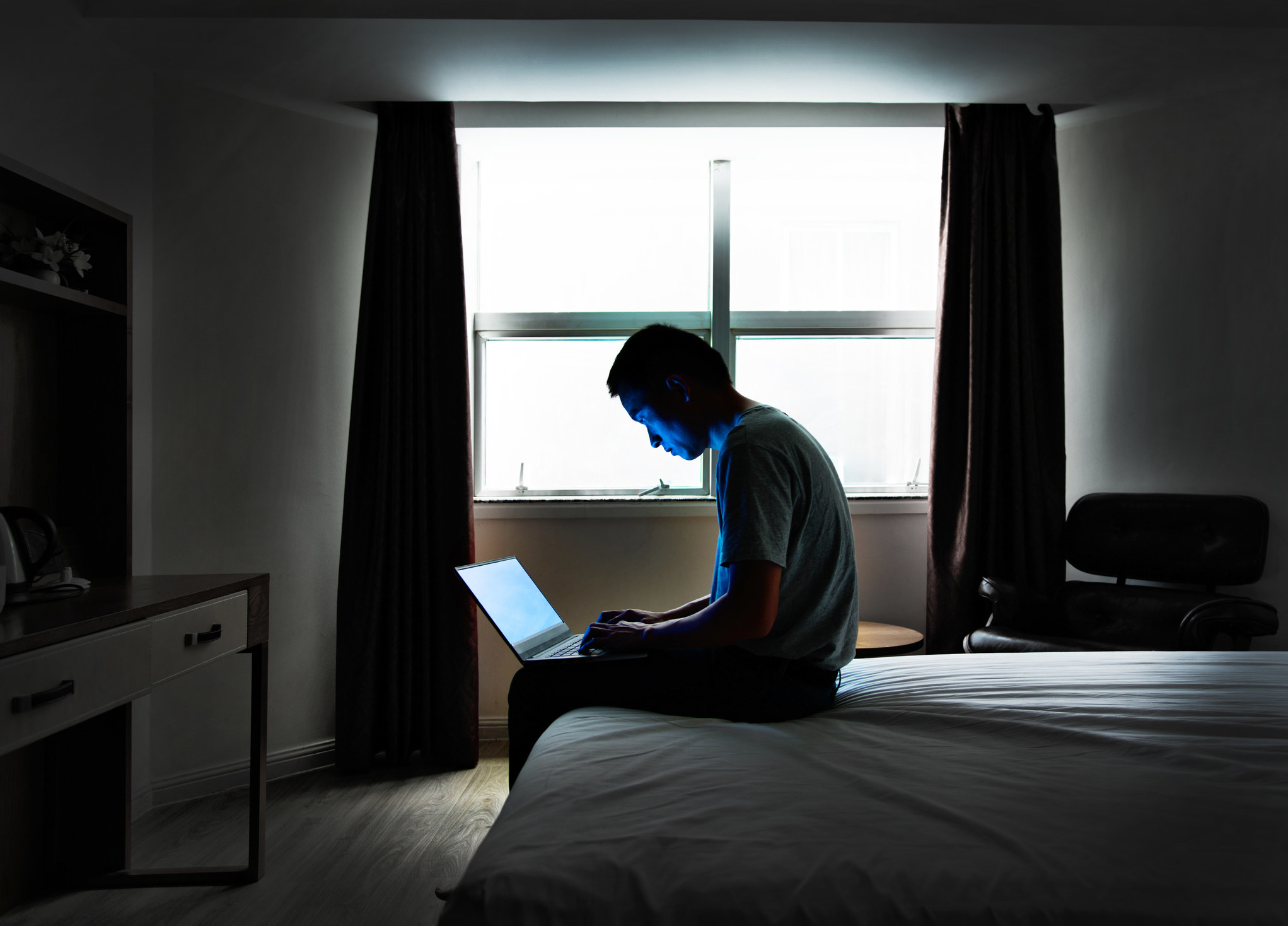 a man on a laptop on his bed