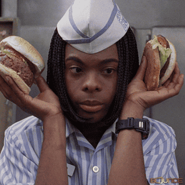 young man holding a burger on either side of his head