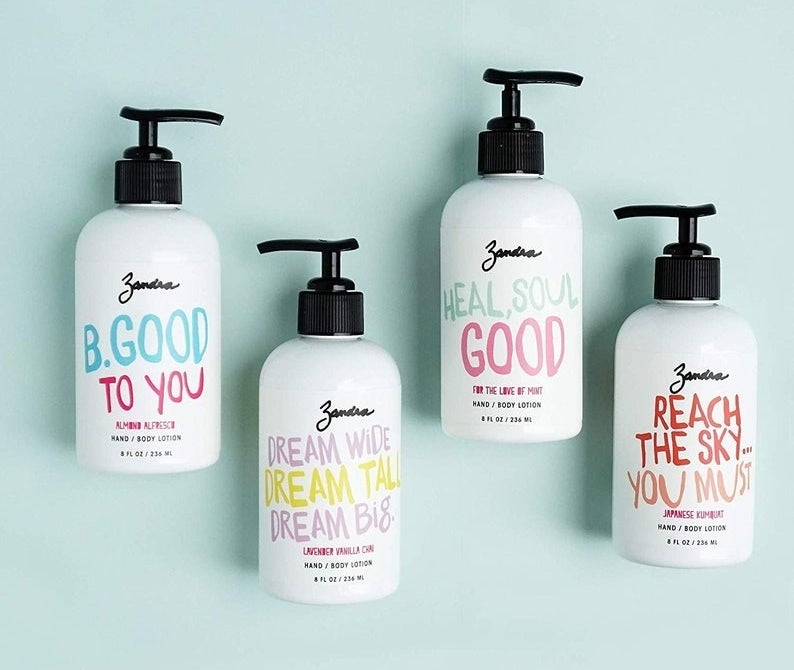 Four bottles of lotion on a teal background with multicolored inspirational quotes