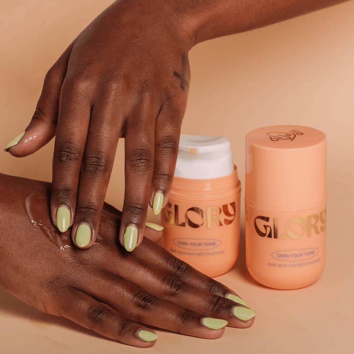 Model applying clear product onto hands next to peach-colored product bottles