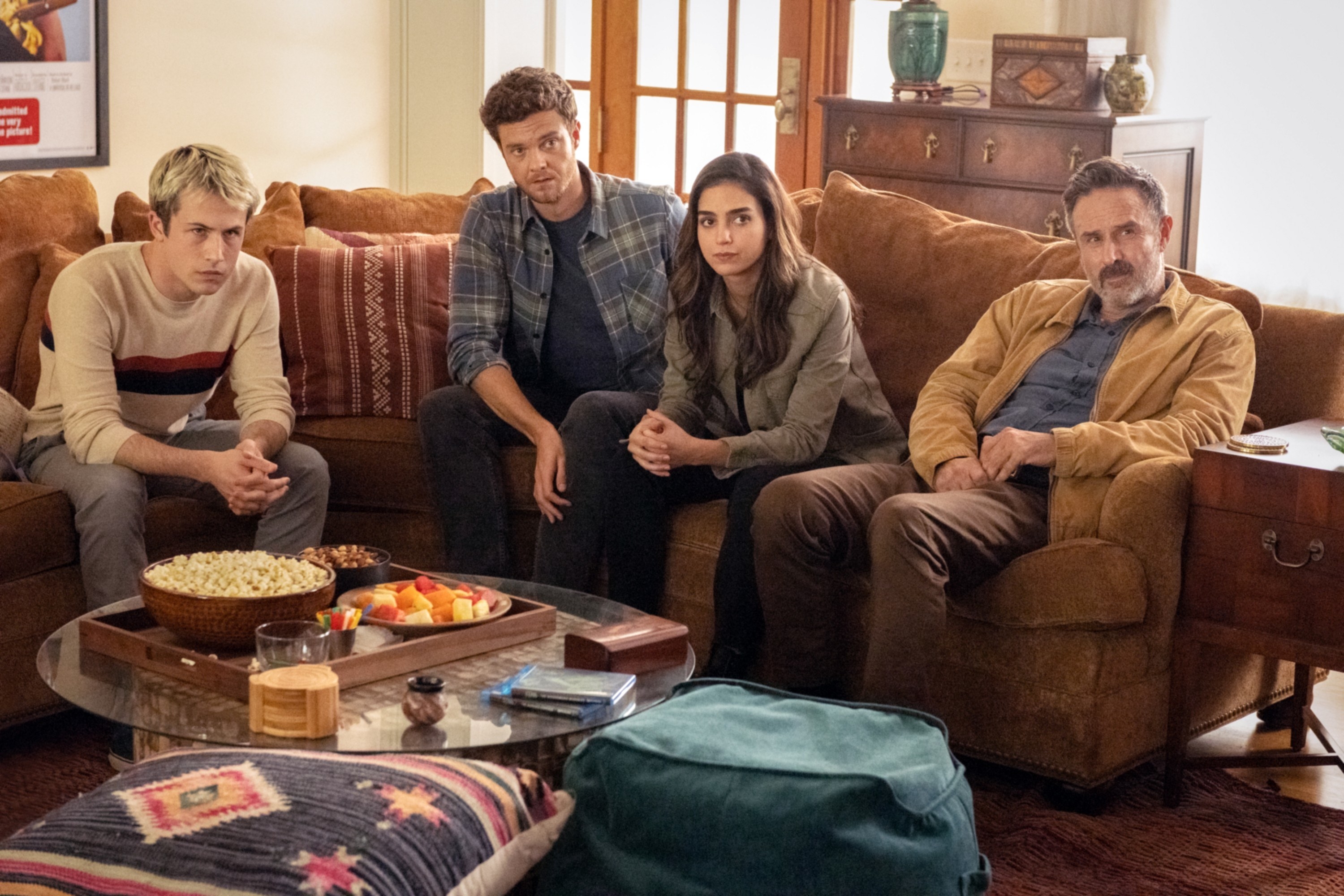 Dylan&#x27;s character sitting with David Arquette and others in a living room in a scene from Scream
