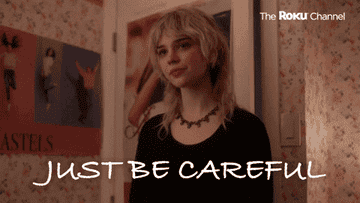 A blonde girl standing in a bedroom saying, &quot;Just be careful&quot;
