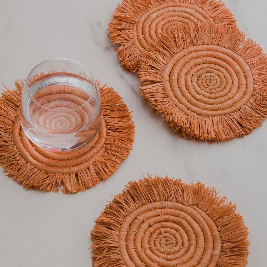 round orange woven coasters with fringe