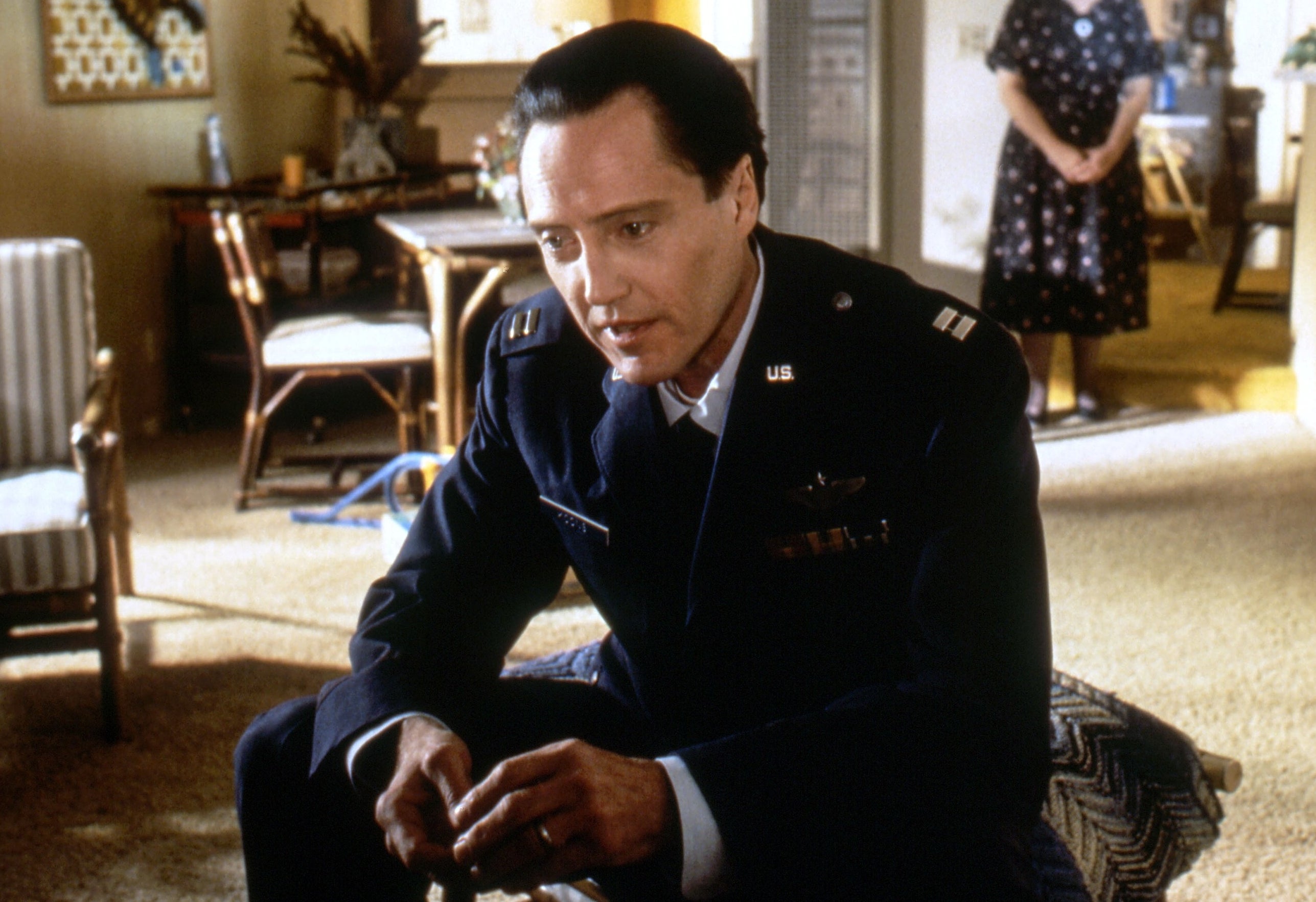 Walken in a military suit, holding a watch talking to a kid