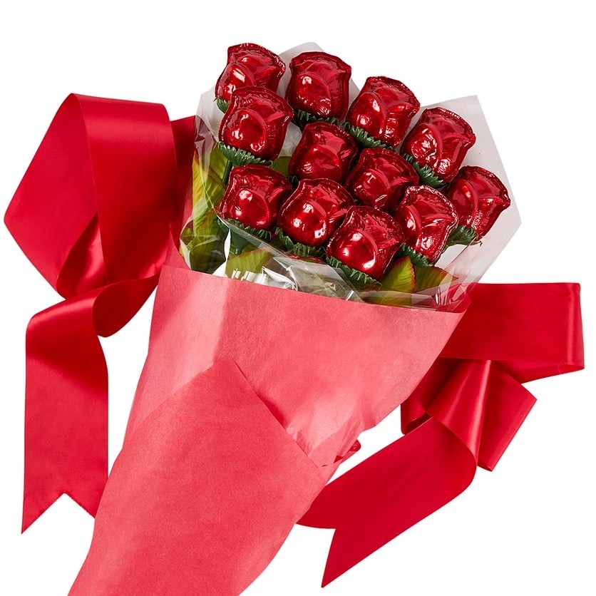 a dozen chocolate roses in red tin foil cradled in a red paper wrap with ribbon