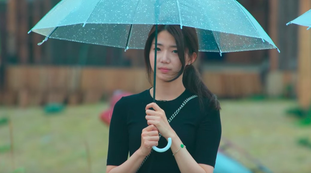 Ji-yeon frowns in the rain holding an umbrella