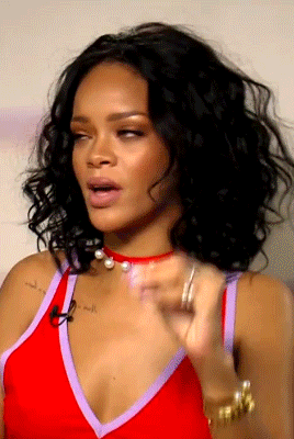 Rihanna sits in her chair and leans against the arm before squinting and saying