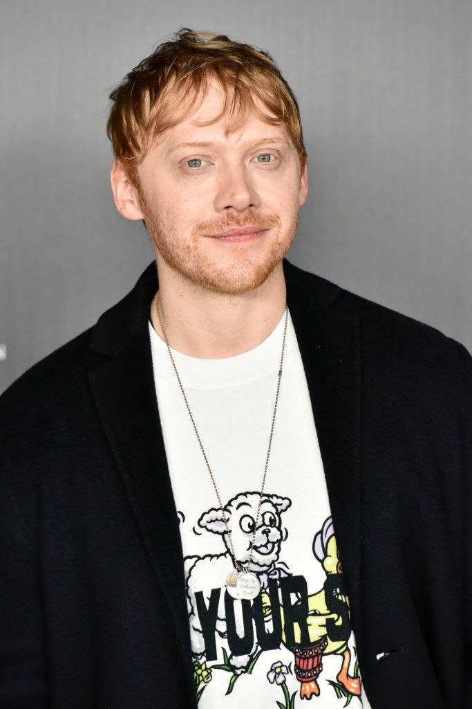 Rupert Grint smiling at an event and wearing a blazer with a t-shirt with a lamb on it