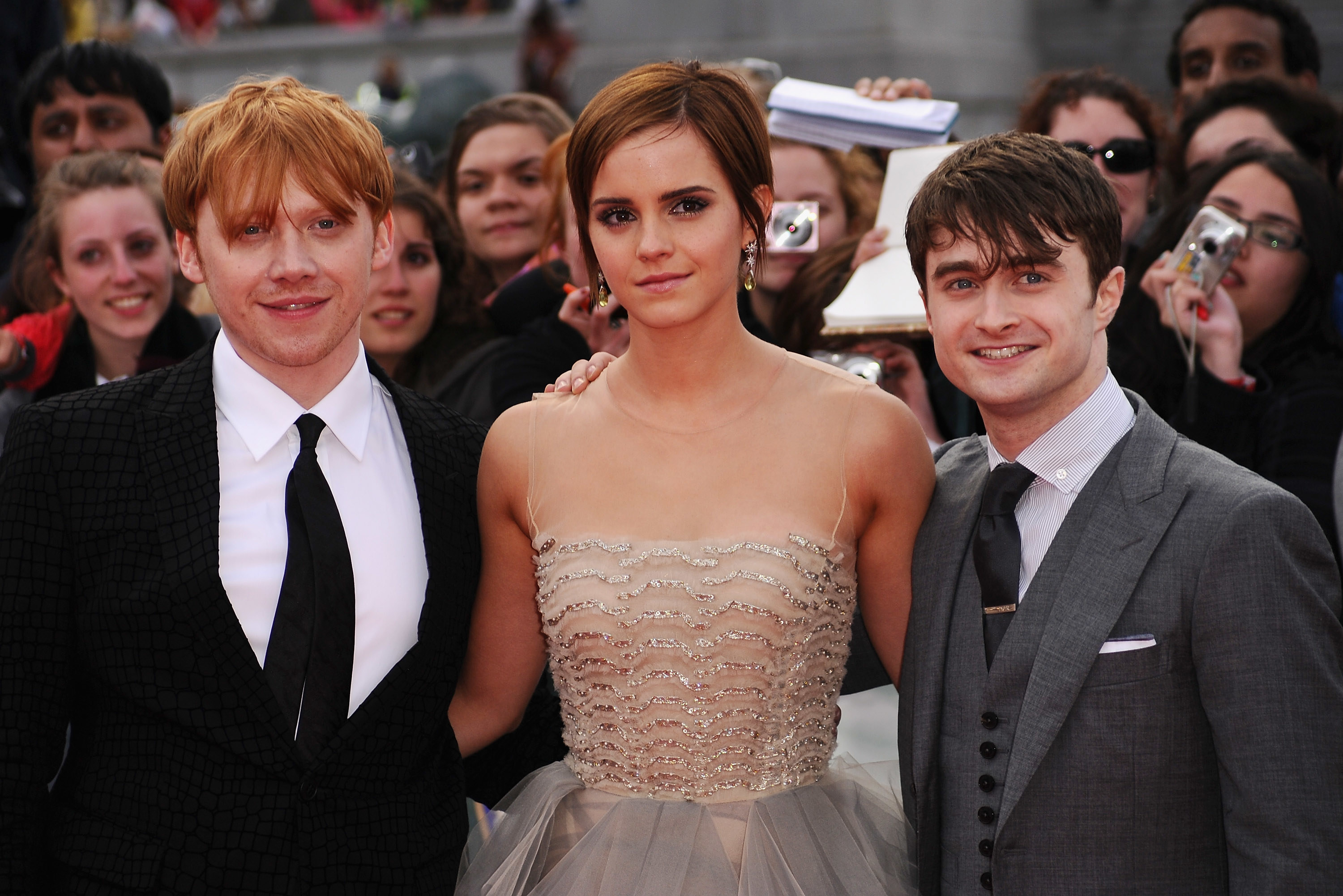 The three cast members standing together on the red carpet at the premiere of one of the Harry Potter films