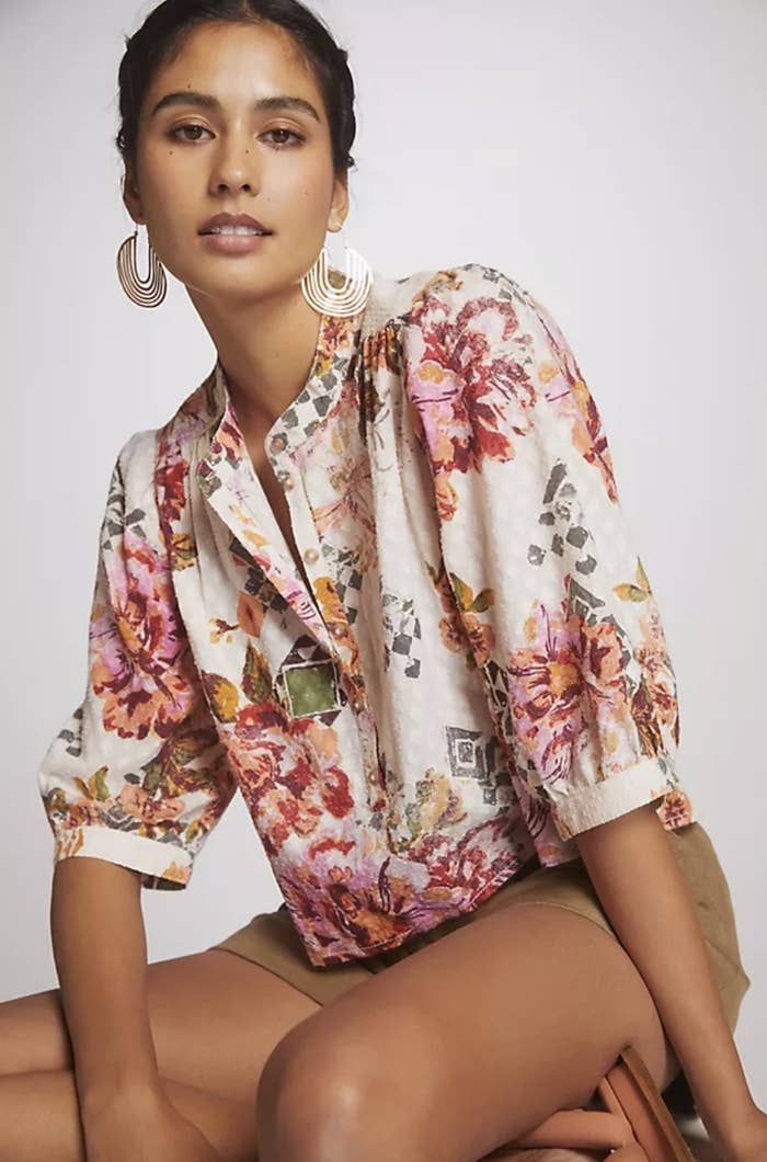 An adult wears the white, pink and green floral blouse