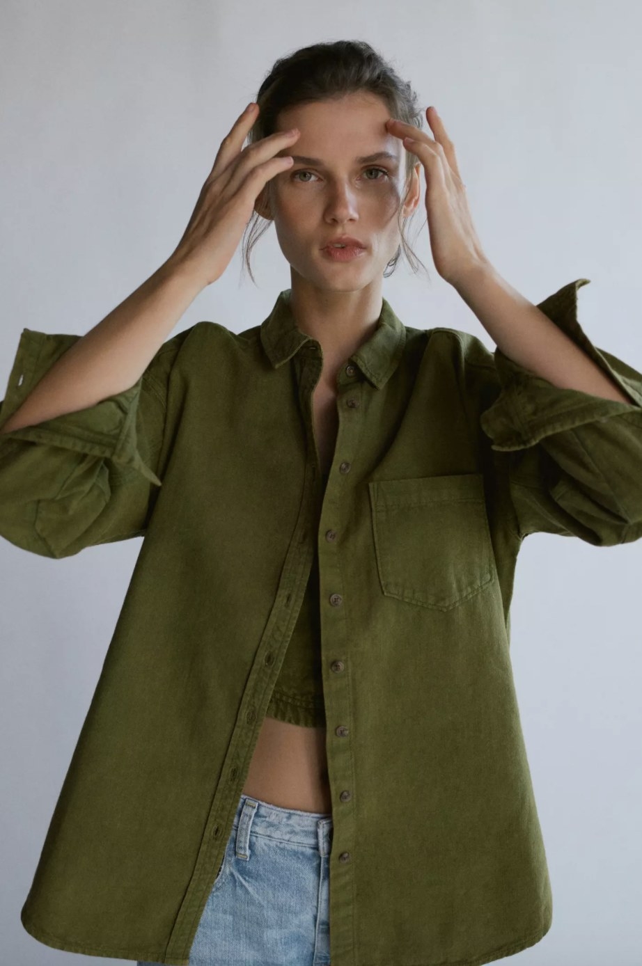 An adult is wearing the olive green tunic top