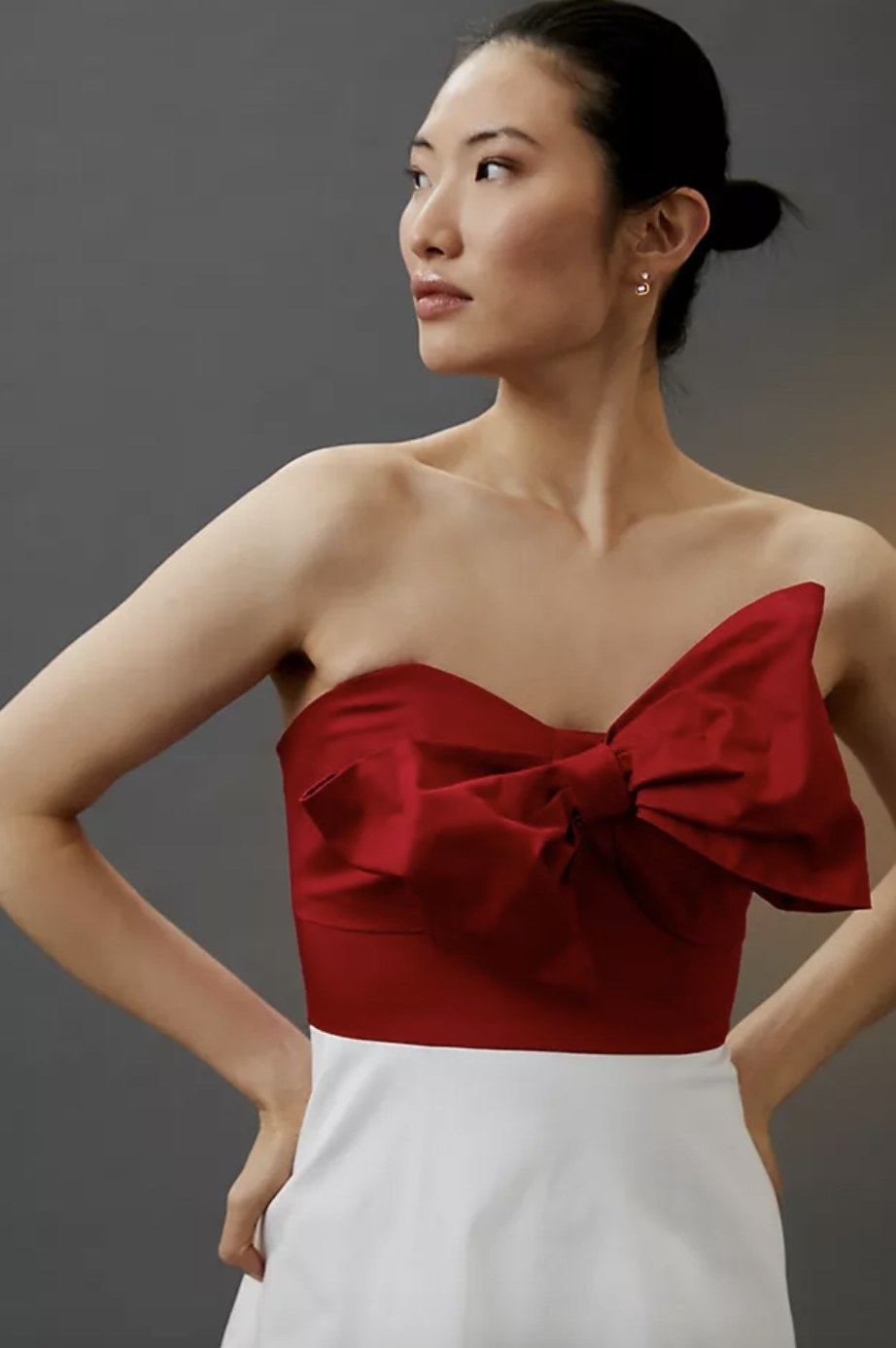An adult wears a red top with a large bow and a white skirt