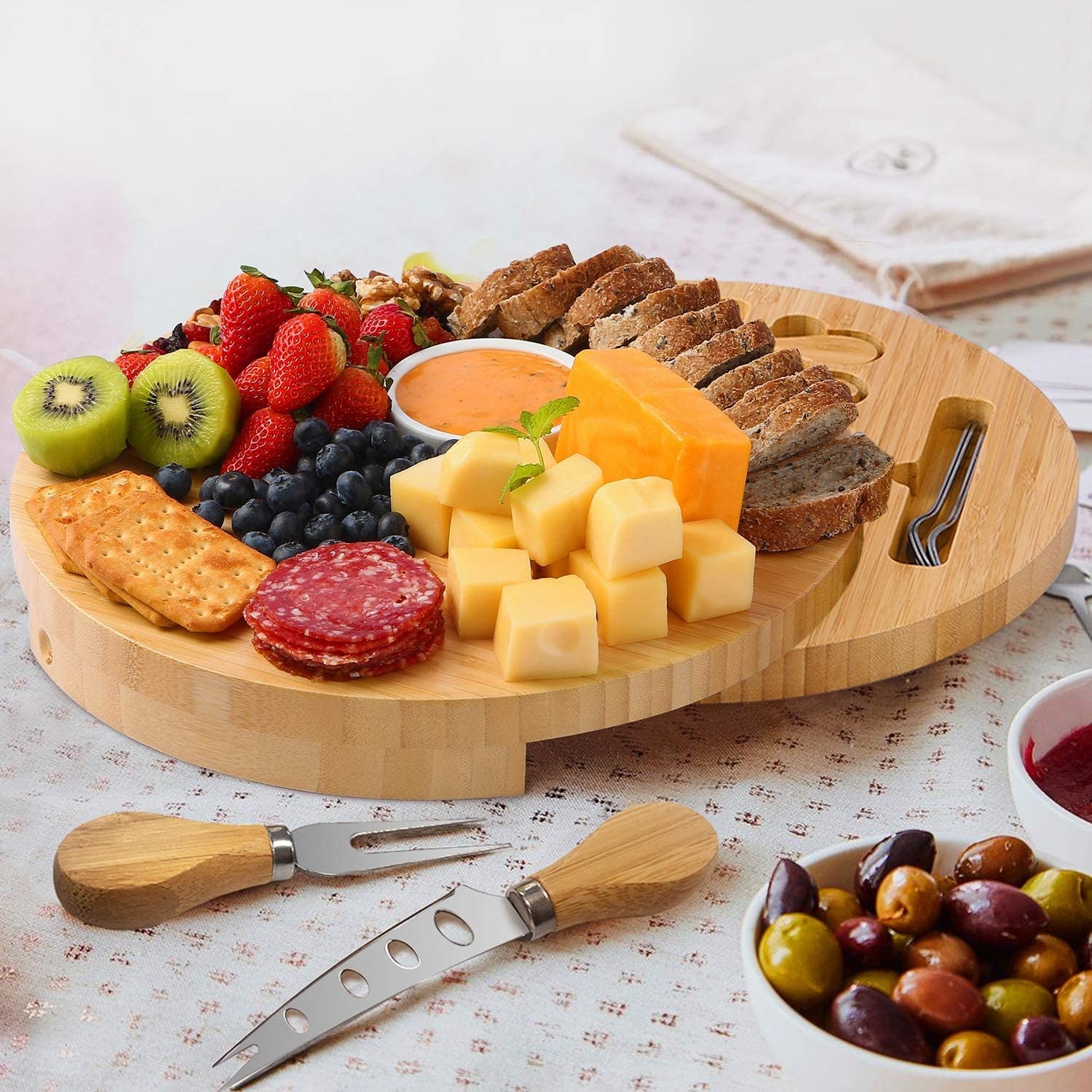 A round wooden board filled with cheese, fruit, meats, and bread