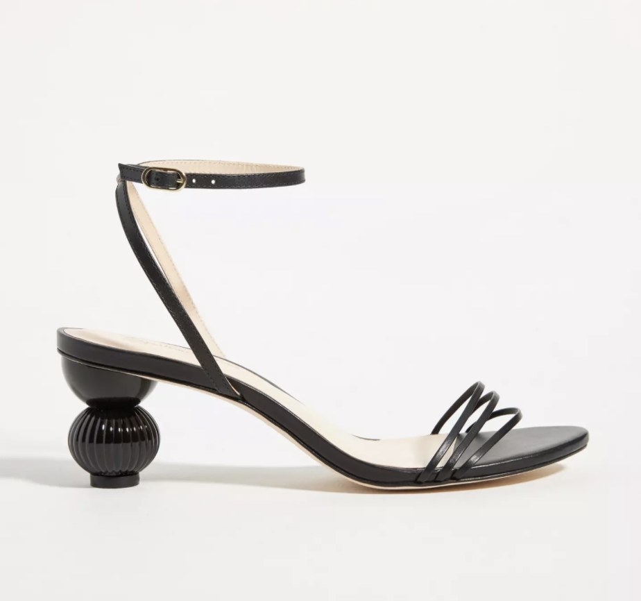 The black heels have a ridged ball heel and three thin straps above the toes