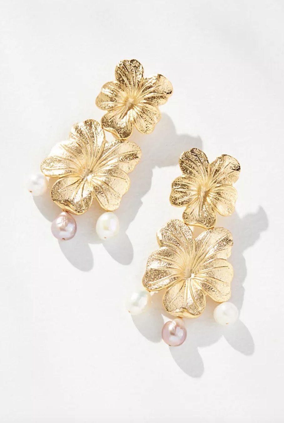The gold earrings have two gold floral accents and three freshwater pearls on each one