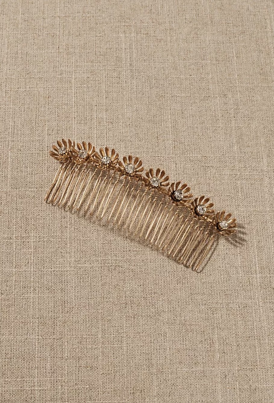 The hold comb has eight gold flowers adorned along the top with a crystal in the center of each one