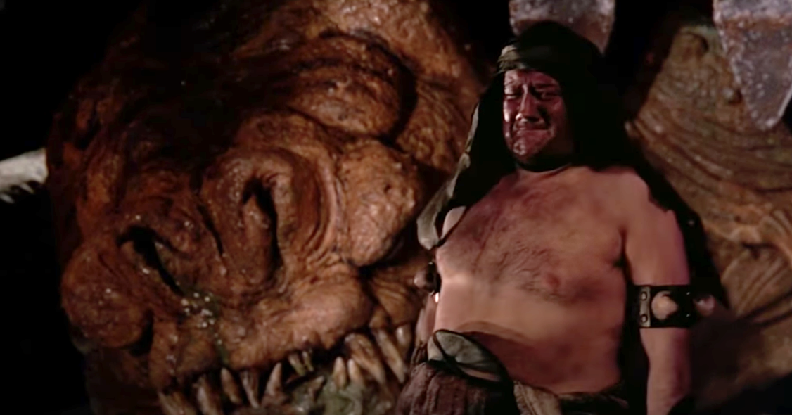 A rancor keeper with no shirt, and a headdress, crying because his rancor is dead