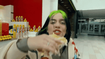 Billie Eilish eating fries with a handful of food court food, as she&#x27;s walking in mall