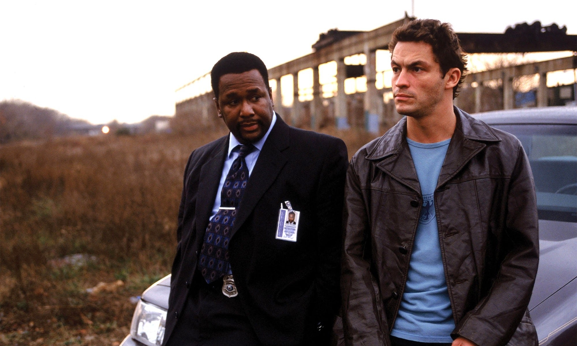 Wendell Pierce as Detective Bunk Moreland and Dominic West as Detective Jimmy McNulty stood by their car near an abandoned building in &quot;The Wire&quot;