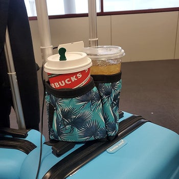a reviewer photo of a suitcase with the drink caddy mounted on it with two drinks inside