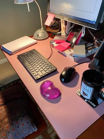 a reviewer image of the pink desk mat with monitor, keyboard, mouse, and more on it