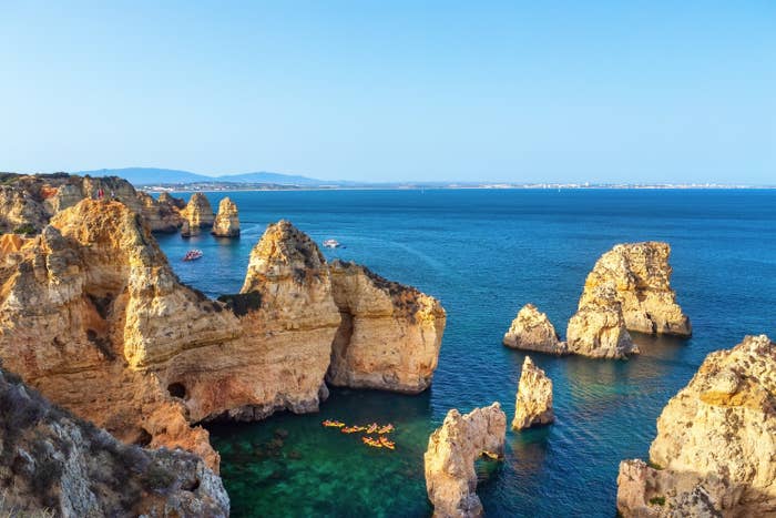 Coastal cliff view with kayaks in the water of Ponta da Piedade, Lagos, Portugal.