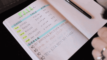 A hand using different colored highlighter markers to write goals in a journal