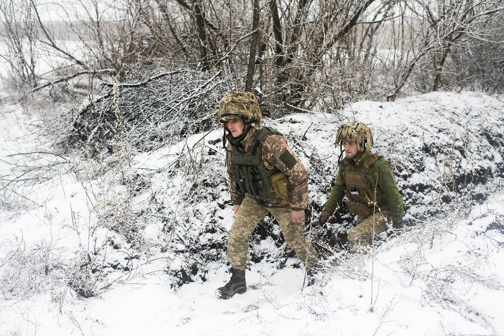 Two young soldiers walking through the woods near trenches